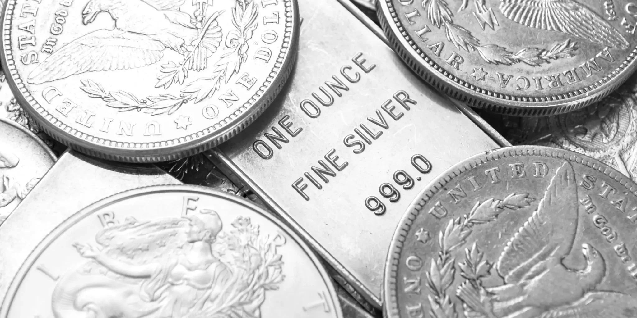 Fine silver bar and assorted silver coins up close, illustrating 999.0 purity precious metals and collectibles.