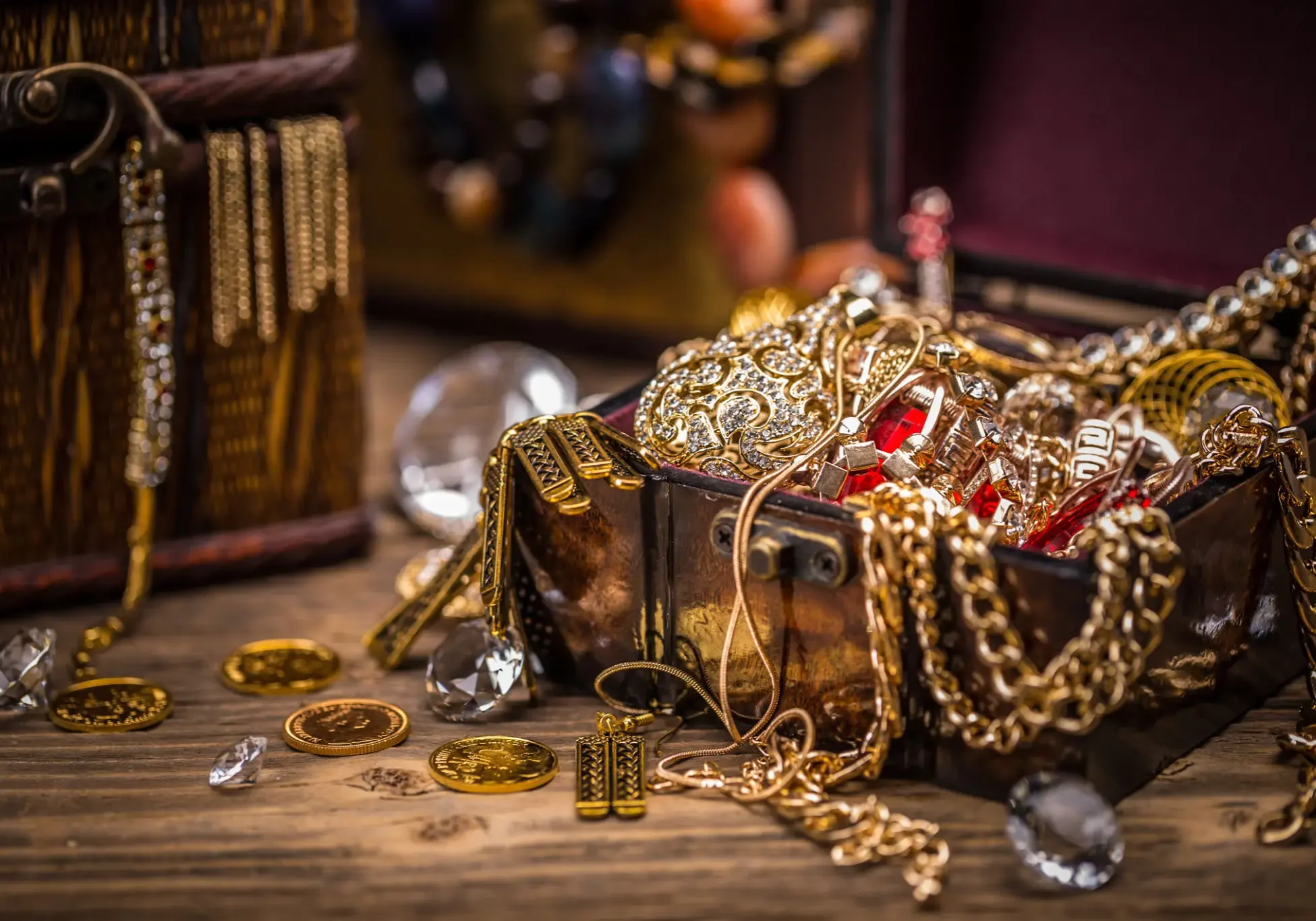 Gold necklaces, chains, coins, and gemstone jewelry spilling from an antique chest, showcasing precious metals and valuables.