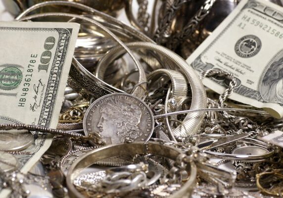 U.S. currency and assorted silver jewelry and coins on display, illustrating precious metals and valuables.